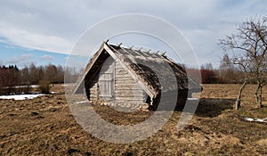 old wooden cellar on the stones covered with a thatched roof