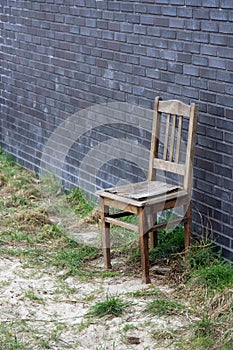 Old wooden chair against brick wall
