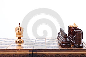 Old wooden Chessboard with lonely King versus opposing team, white background, copy space