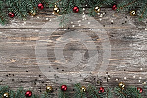 Old wooden Christmas background. Fir branches with baubles and gold stars. Space for text. Top view
