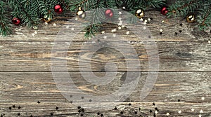 Old wooden Christmas background. Fir branches with baubles and gold stars. Space for text. Top view