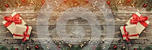 Old wooden Christmas background. Fir branches with baubles and gold stars. Xmas gifts. Top view. Light effect