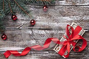 An old wooden Christmas background, a fir tree with baubles, money embellished with red slack