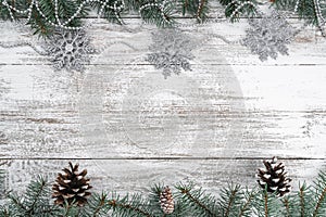 Old wooden Christmas background. Garlands and snowflakes. Fir branches and cones. Xmas greeting card. Top view