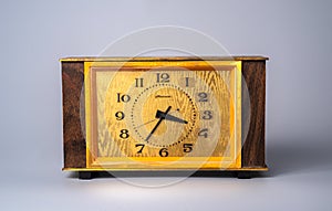 Old wooden clock with with dial in yellow frame and black hands and numbers. Brown vintage watch from USSR with wooden