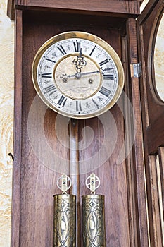 Old wooden clock with a pendulum hanging