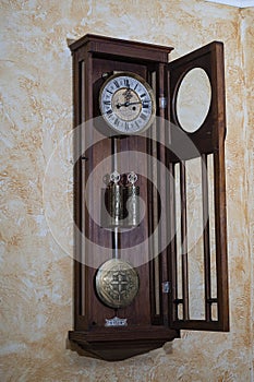 Old wooden clock with a pendulum hanging on