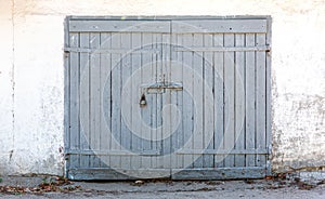 Old wooden closed gate on white painted plaster wall