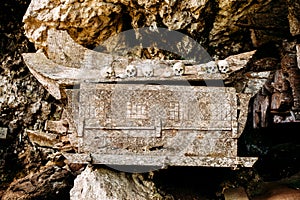 Old wooden coffin with skulls and bones nearby on a rock. Hanging coffins, graves. Traditional burials site, cemetery Kete Kesu in