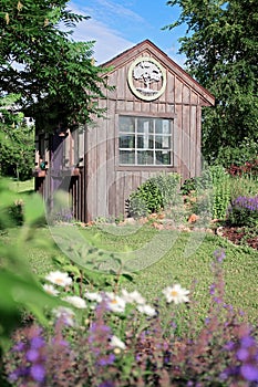 Old Wooden Cottage Style Shed near Flowers in a Country Garden