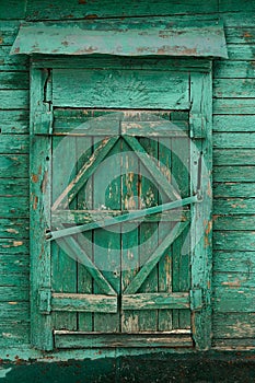 Old wooden country window with closed shutters painted green