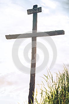 Old wooden cross at country road, blue sky