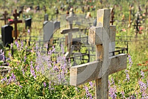 Old wooden cross on overgrown grave