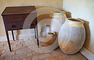 An old wooden desk and vintage ceramic crocks on the floor
