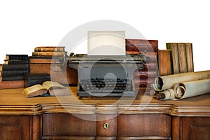 Desk with vintage typewriter holding an empty sheet of paper and ancient books and maps