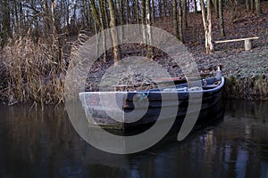 Old wooden dinghy moored to the shore of a lake