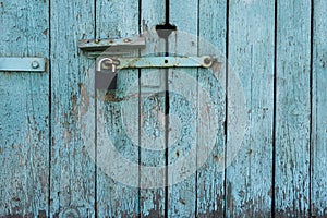 Old wooden door with blue painted planks closed with a padlock. Grunge background