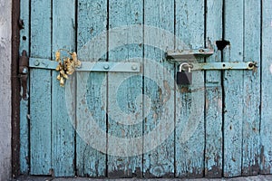 Old wooden door with blue painted planks closed with a padlock. Grunge background