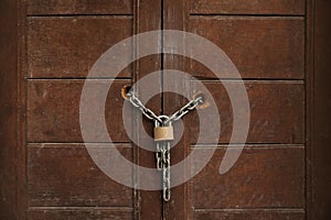 Old wooden door with chain and lock, closeup view