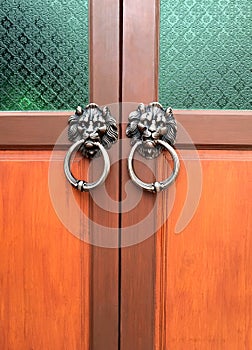 Old wooden door decorated with a lion head as a knocker