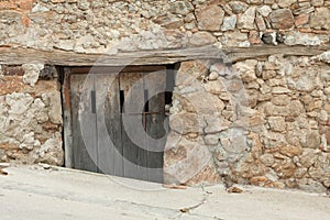 An old wooden door of the entrance to a warehouse and stable located in the basement of an old house