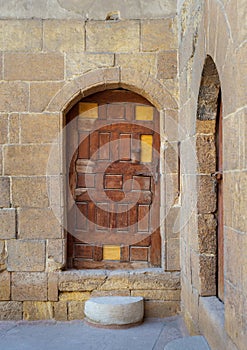 Old wooden door framed by arched bricks stone wall, Darb al Ahmar district, Old Cairo, Egypt