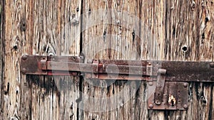 An old wooden door with a hinged vintage iron bolt. Rusty massive iron lock