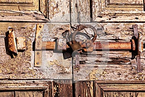 Old wooden door with iron rusty latch and padlock