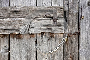 Old wooden door locked with chains and padlocks in Tonadico town, Primiero San Martino di Castrozza. Italy, Europe.