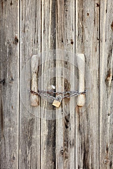 Old wooden door locked with rusty chain and a padlock