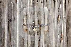 Old wooden door locked with rusty chain and padlock