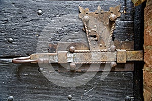 Old wooden door with metal knob and rusty medieval bolt.