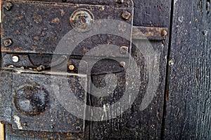 Old wooden door with metal knob and rusty medieval bolt.