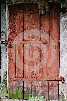 Old wooden door is not closed on the lock. Peeling paint. House.