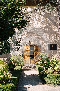 Old wooden door open and the facade of the Medici Villa of Lilliano Wine Estate, Tuscany, Italy under the shade of trees