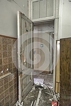 An old wooden door in a room of an abandoned house. Shabby walls.