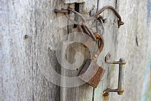 Old wooden door with rusty handle, hook and lock