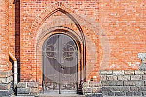 Old wooden door, rusty hinges and lock, brick wall