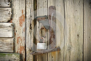 Old Wooden Door With A Rusty Steel Lock. Farm Gate From Planks With An Old Padlock. The Lock On The Door Of The Shed