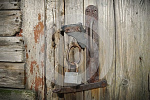 Old Wooden Door With A Rusty Steel Lock. Farm Gate From Planks With An Old Padlock. The Lock On The Door Of The Shed