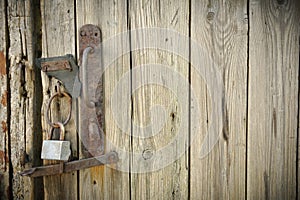 Old Wooden Door With A Rusty Steel Lock. Farm Gate From Planks With An Old Padlock. The Lock On The Door Of The Shed