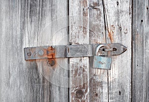 Old wooden door secured by rusty padlock