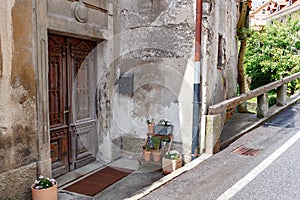 Old wooden door of a shabby demaged house facade. A small town in the mountains of Slovenia, Europe.