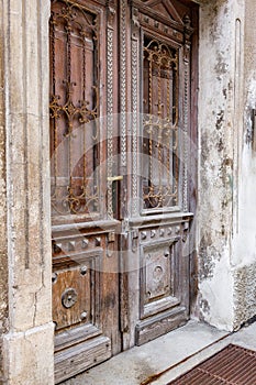 Old wooden door of a shabby demaged house facade. A small town in the mountains of Slovenia, Europe.