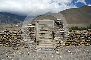Old wooden door in a stone wall against the backdrop of the Himalayan mountains.