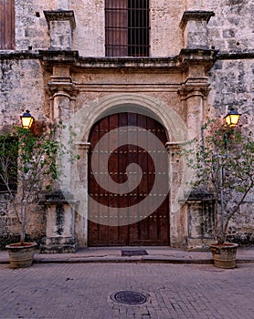 Old Wooden Door Surrounded by Stone With Outdoor Lamps