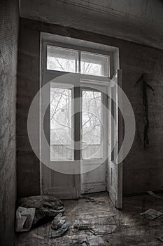 Old wooden door to a balcony in an abandoned house. Monochrome photo.