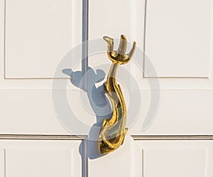 Old wooden door to house with a brass knocker in the shape of a