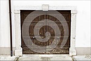 Old wooden door on white wall of ancient building. Palmanova, Italy.