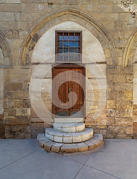 Old wooden door and window framed by arched bricks stone wall at the courtyard of al Razzaz historic house, Old Cairo, Egypt